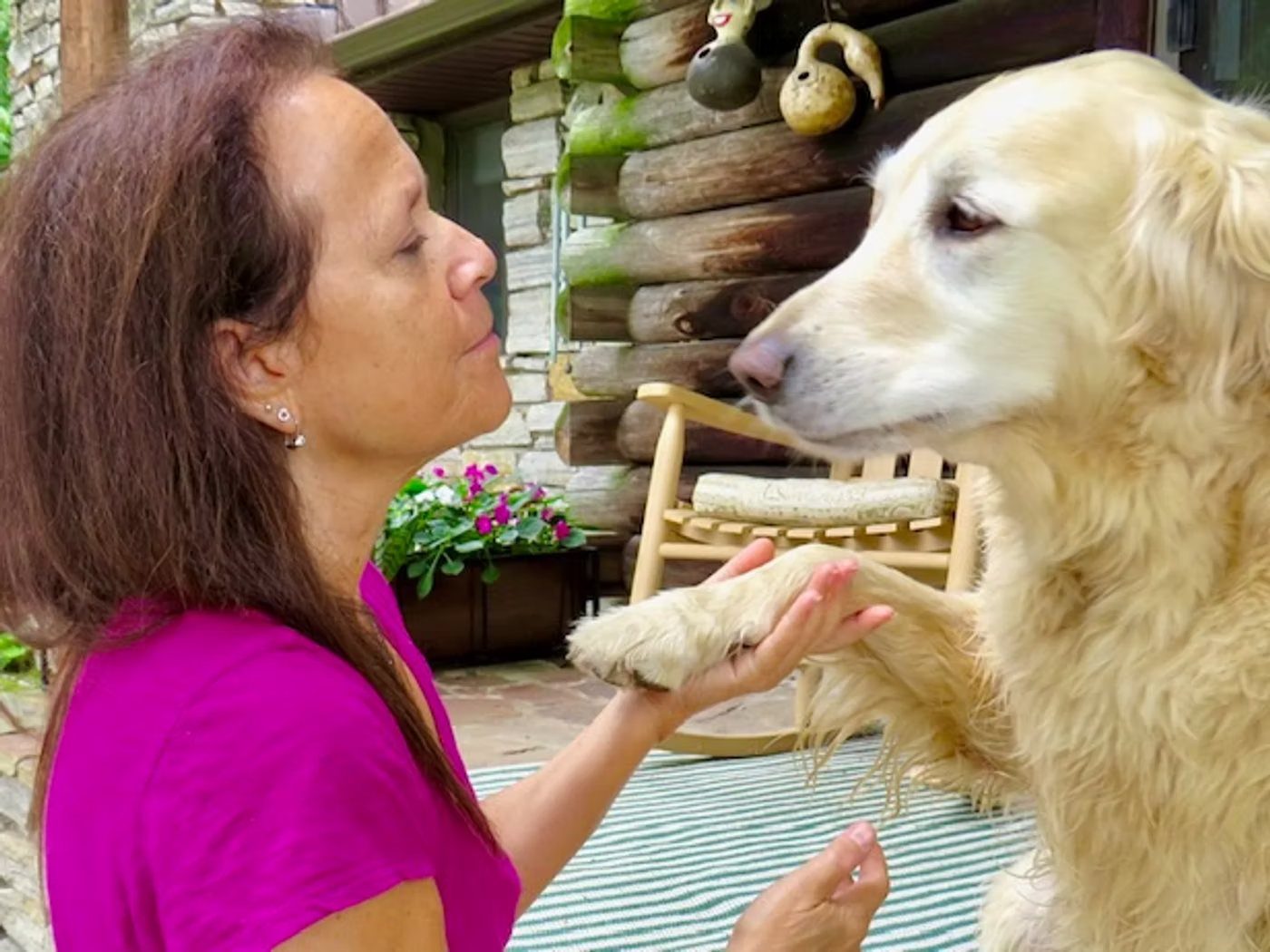 Donna Sue Rosenthal holding a golden retriever's paw, face to face on a porch